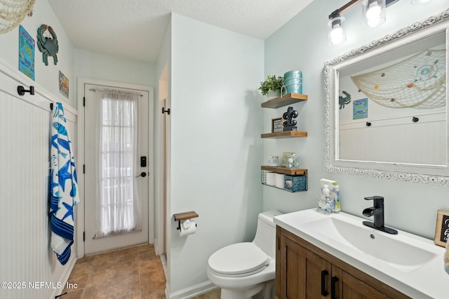 bathroom with vanity, a healthy amount of sunlight, a textured ceiling, and toilet