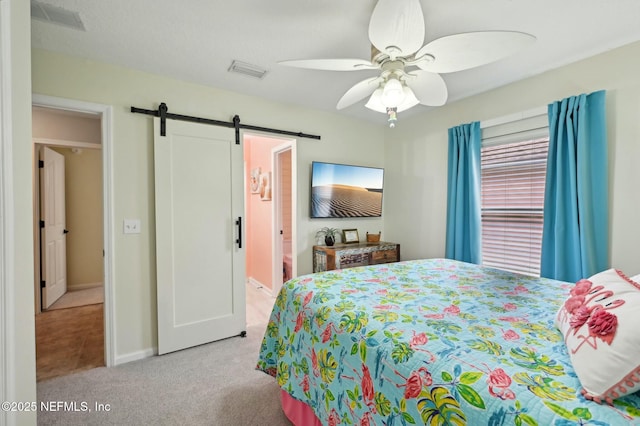 carpeted bedroom with ceiling fan, ensuite bath, and a barn door