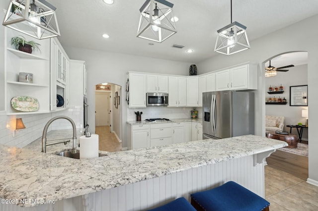 kitchen featuring pendant lighting, sink, appliances with stainless steel finishes, white cabinets, and kitchen peninsula