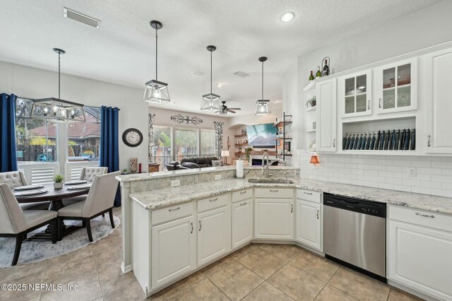 kitchen with tasteful backsplash, dishwasher, sink, white cabinets, and hanging light fixtures