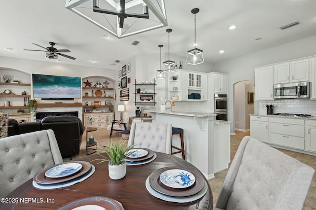 dining room with built in shelves, ceiling fan, and sink