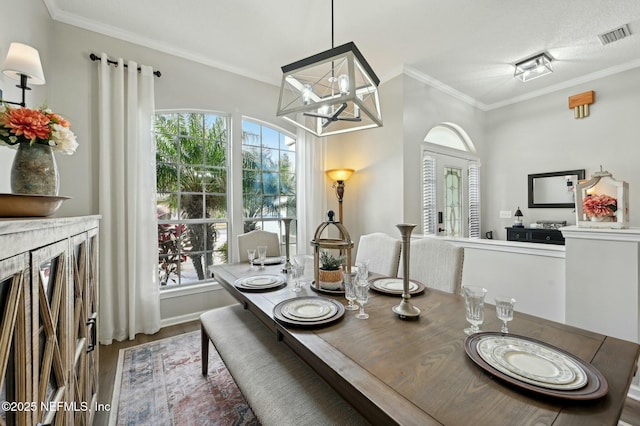 dining area featuring hardwood / wood-style flooring, ornamental molding, a textured ceiling, and a chandelier