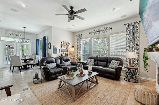 living room featuring light tile patterned flooring, ceiling fan, and a textured ceiling