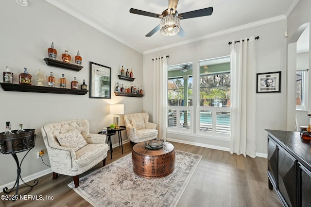 living area with crown molding, dark wood-type flooring, and ceiling fan