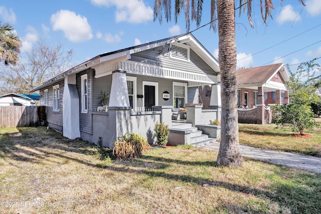 bungalow-style home featuring covered porch and a front yard