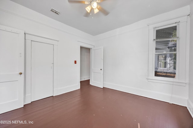 unfurnished bedroom featuring ceiling fan, dark hardwood / wood-style floors, and a closet