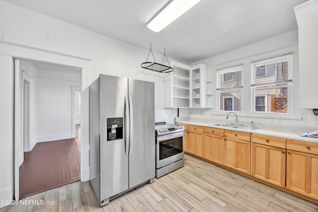 kitchen featuring tasteful backsplash, sink, light wood-type flooring, and appliances with stainless steel finishes