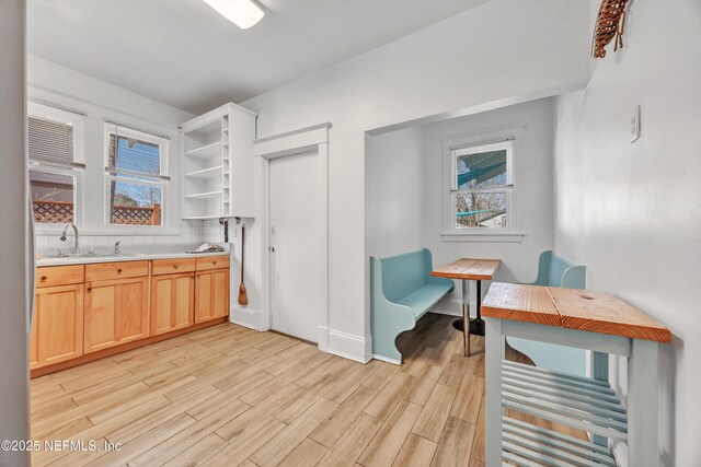 kitchen with light brown cabinetry, sink, light hardwood / wood-style flooring, and tasteful backsplash