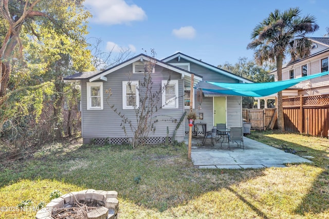 back of property with a yard, a patio area, and a fire pit