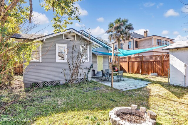 rear view of house with a patio, a lawn, and an outdoor fire pit