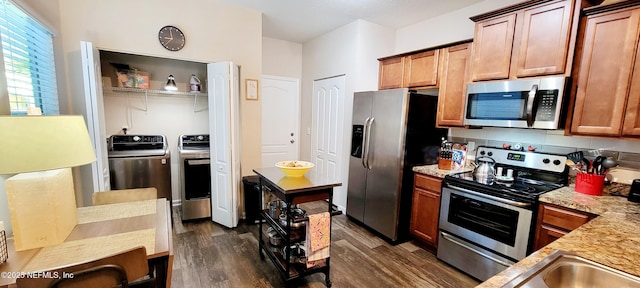 kitchen with appliances with stainless steel finishes, dark hardwood / wood-style floors, decorative backsplash, light stone counters, and washing machine and dryer