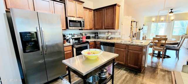 kitchen featuring a kitchen island, sink, hardwood / wood-style flooring, hanging light fixtures, and stainless steel appliances