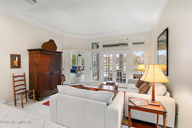 tiled living room with a tray ceiling, crown molding, and french doors