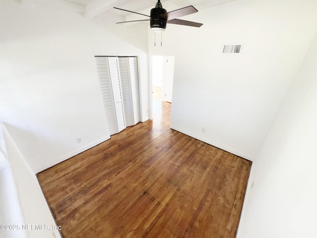 unfurnished room featuring wood-type flooring, beamed ceiling, and ceiling fan