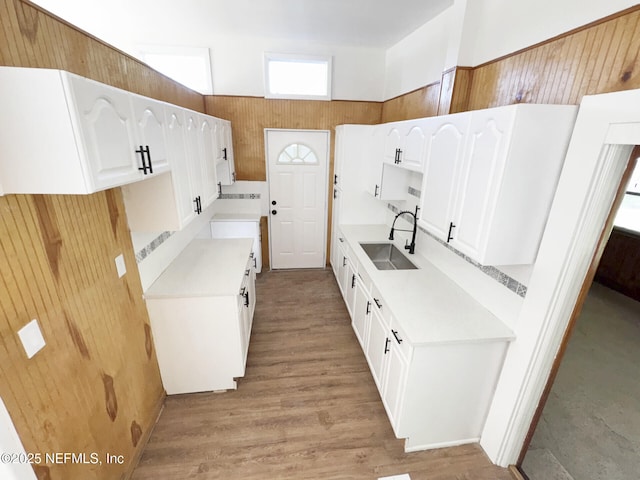 kitchen with sink, white cabinets, light hardwood / wood-style flooring, and a towering ceiling