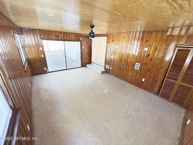 interior space featuring wood ceiling, ceiling fan, and wooden walls