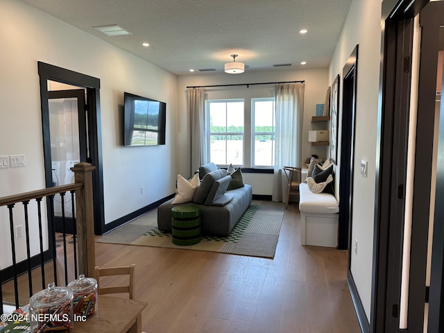 living room featuring light wood-type flooring and a textured ceiling