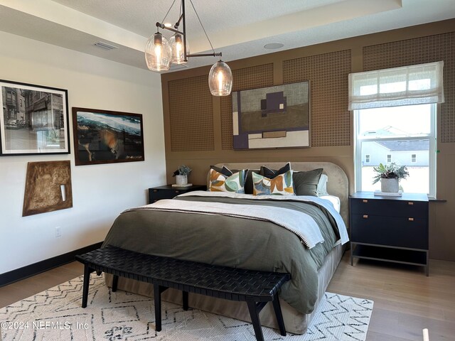 bedroom featuring light hardwood / wood-style floors and a raised ceiling