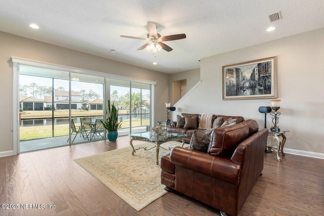 living room featuring ceiling fan, dark wood-type flooring, and a textured ceiling