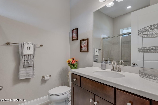 bathroom featuring vanity, a shower with door, and toilet