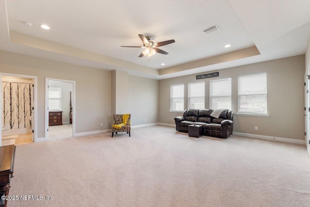 sitting room with ceiling fan, light colored carpet, and a tray ceiling