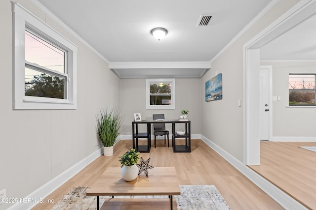 sitting room with light wood-type flooring, ornamental molding, and a healthy amount of sunlight