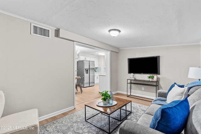 living room with wood-type flooring, a textured ceiling, and ornamental molding