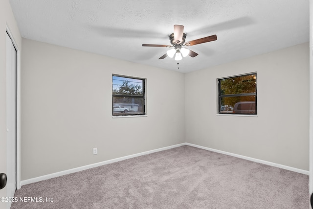 carpeted empty room with ceiling fan and a textured ceiling