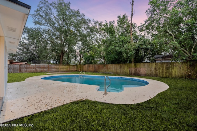 pool at dusk with a patio and a yard