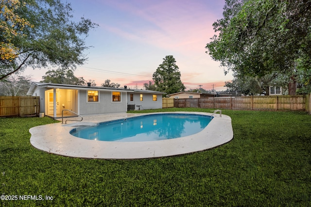 pool at dusk featuring a patio and a yard