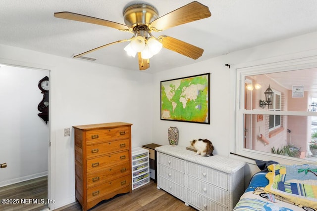 bedroom with ceiling fan, dark wood-type flooring, and a textured ceiling