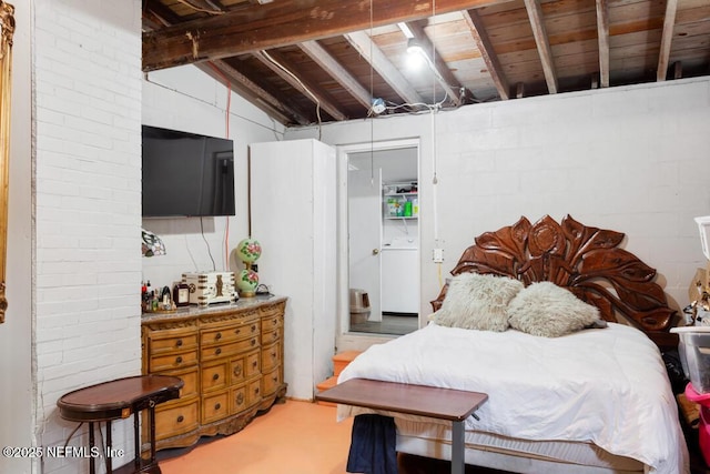 bedroom featuring washer / dryer, concrete flooring, and vaulted ceiling