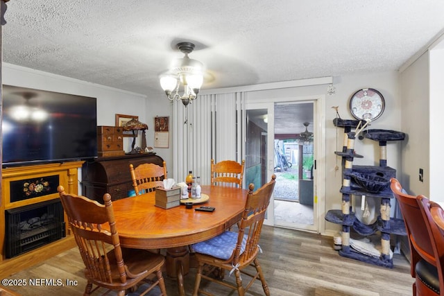 dining room featuring a textured ceiling, ornamental molding, hardwood / wood-style floors, and an inviting chandelier