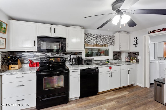 kitchen featuring black appliances, washer and clothes dryer, and white cabinets