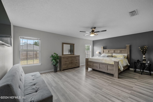 bedroom featuring ceiling fan, light hardwood / wood-style floors, and a textured ceiling