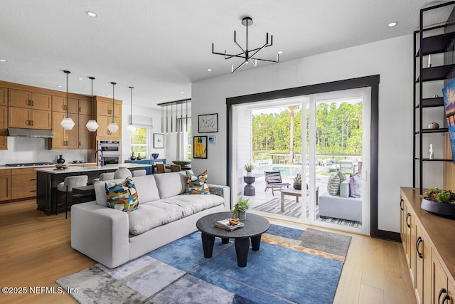 living room with an inviting chandelier, light hardwood / wood-style floors, and a textured ceiling