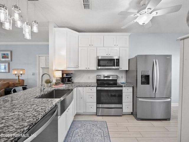 kitchen featuring sink, stainless steel appliances, white cabinetry, and hanging light fixtures