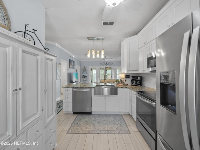 kitchen with kitchen peninsula, white cabinets, decorative light fixtures, and stainless steel appliances