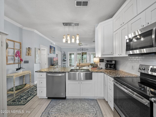 kitchen featuring sink, white cabinets, kitchen peninsula, and appliances with stainless steel finishes