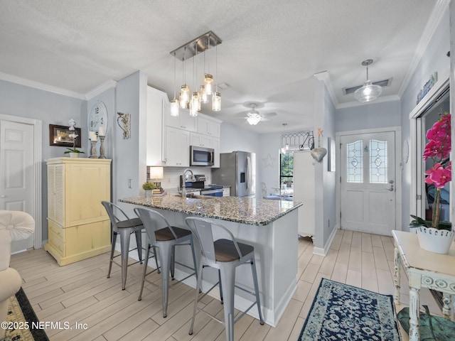 kitchen with stainless steel appliances, white cabinetry, pendant lighting, and a textured ceiling