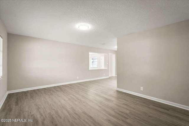 unfurnished room with a textured ceiling and dark wood-type flooring