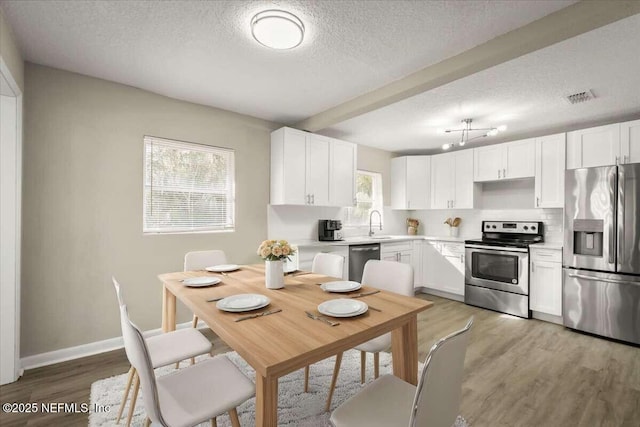 kitchen featuring stainless steel appliances, white cabinets, decorative backsplash, light hardwood / wood-style floors, and sink