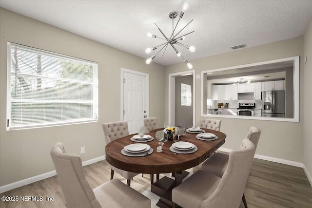 dining space featuring a chandelier, a textured ceiling, and hardwood / wood-style floors