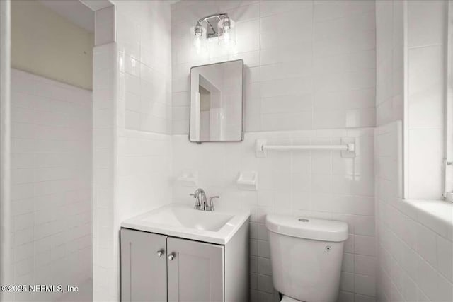 bathroom with vanity, tile walls, and toilet