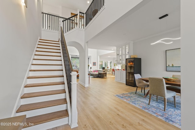 stairway with a towering ceiling, ornamental molding, and hardwood / wood-style floors