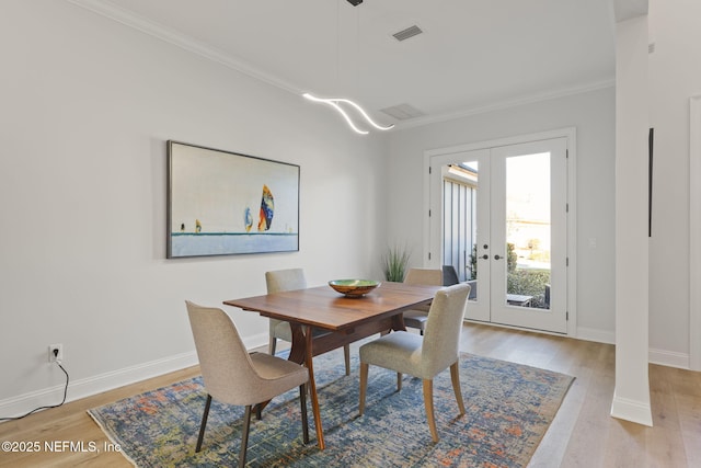 dining area featuring french doors, ornamental molding, and light hardwood / wood-style floors