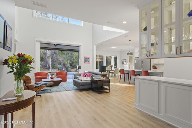 living room featuring a healthy amount of sunlight, light wood-type flooring, and a towering ceiling