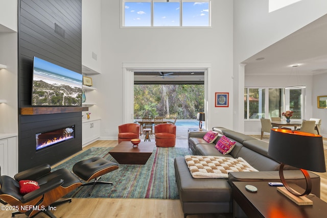 living room featuring wood-type flooring, a fireplace, and a high ceiling