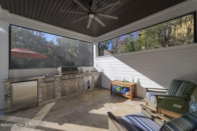 view of patio featuring ceiling fan, area for grilling, and exterior kitchen