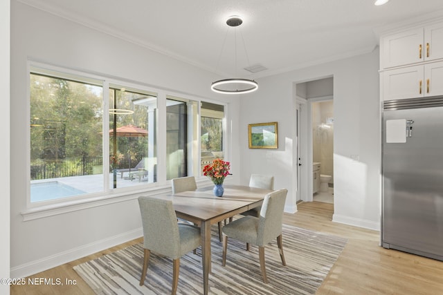 dining space with ornamental molding and light hardwood / wood-style floors